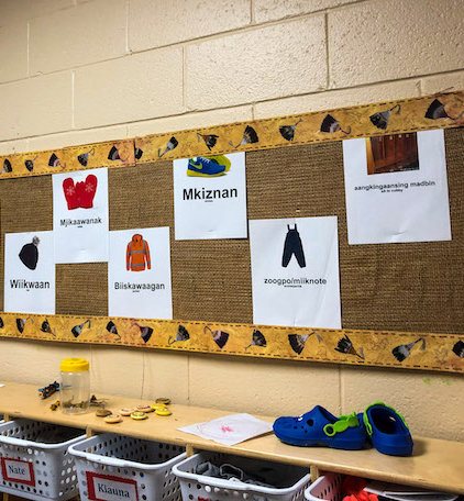 Anishinaabemowin language learning board with clothing vocabulary displayed at Enji Maajtaawaad Early Years Centre classroom.