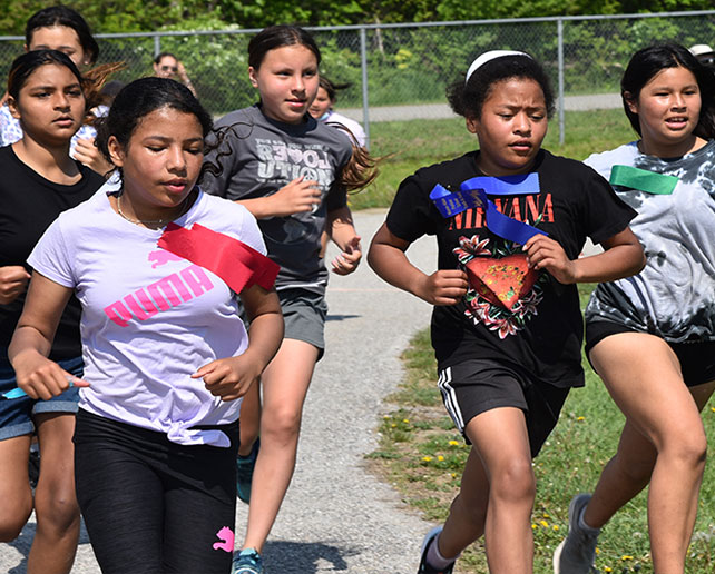 Students running together during a community track and field day.