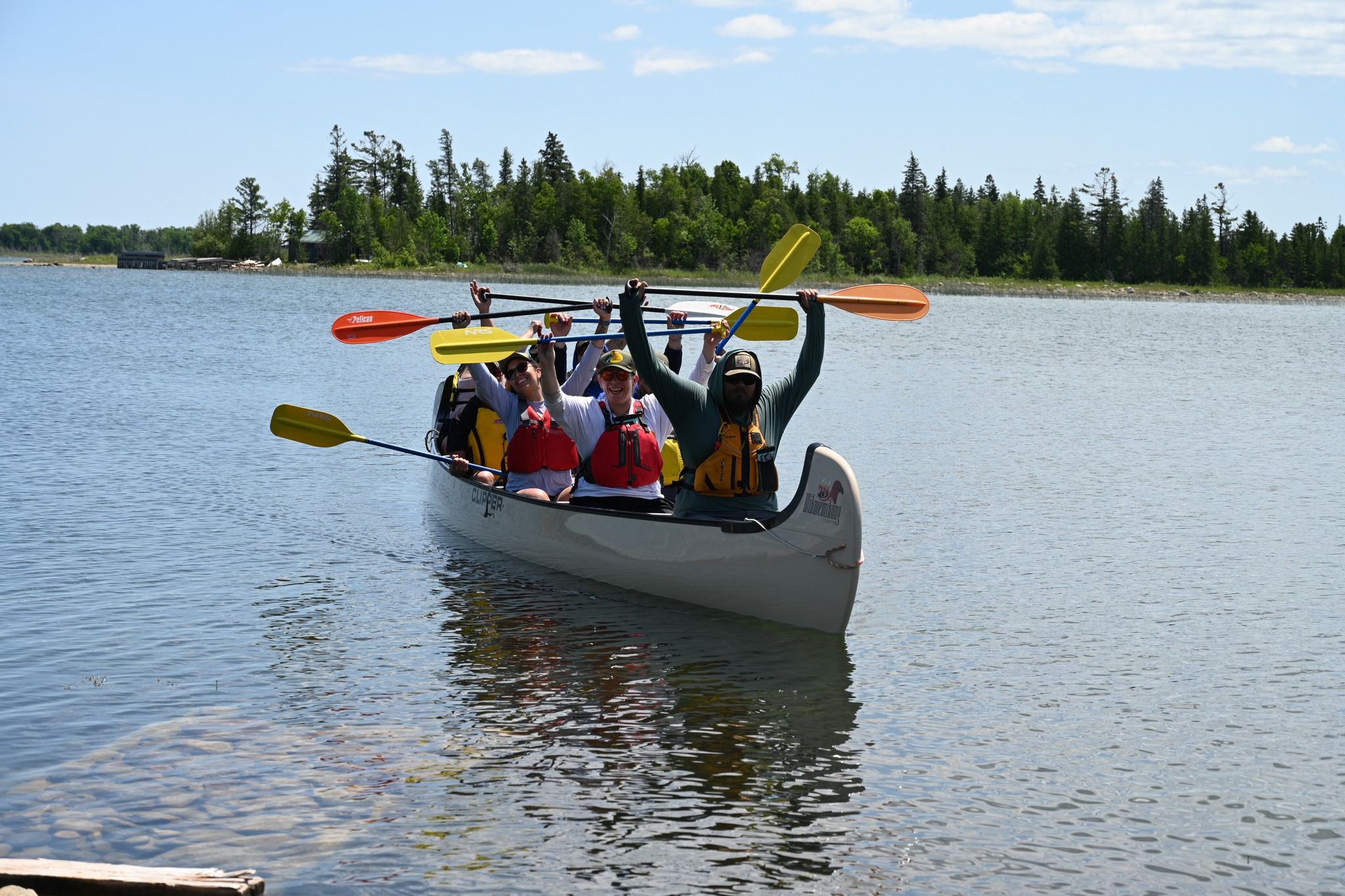 Students in a canoe with paddles overhead in victory